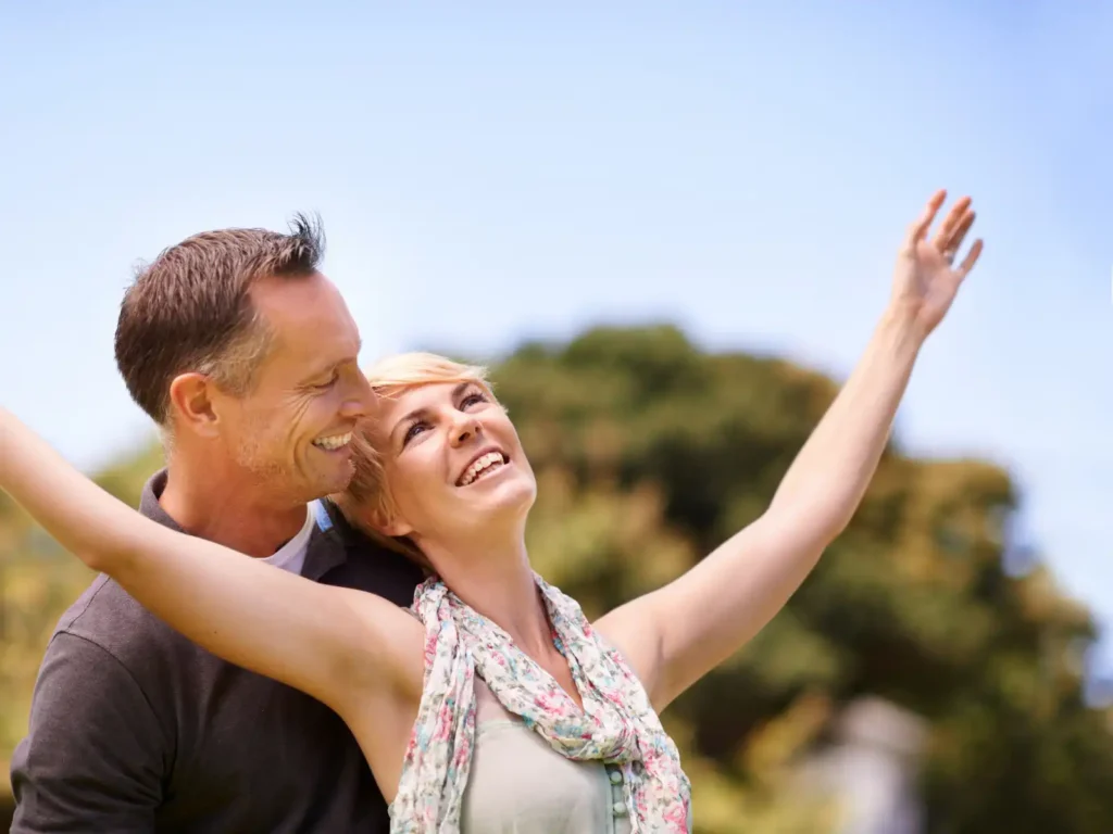 A happy couple embraces outdoors, with the woman joyfully raising her arms, symbolizing the positive transformation and deeper emotional connection achieved through Emotionally Focused Therapy (EFT) in Los Angeles.