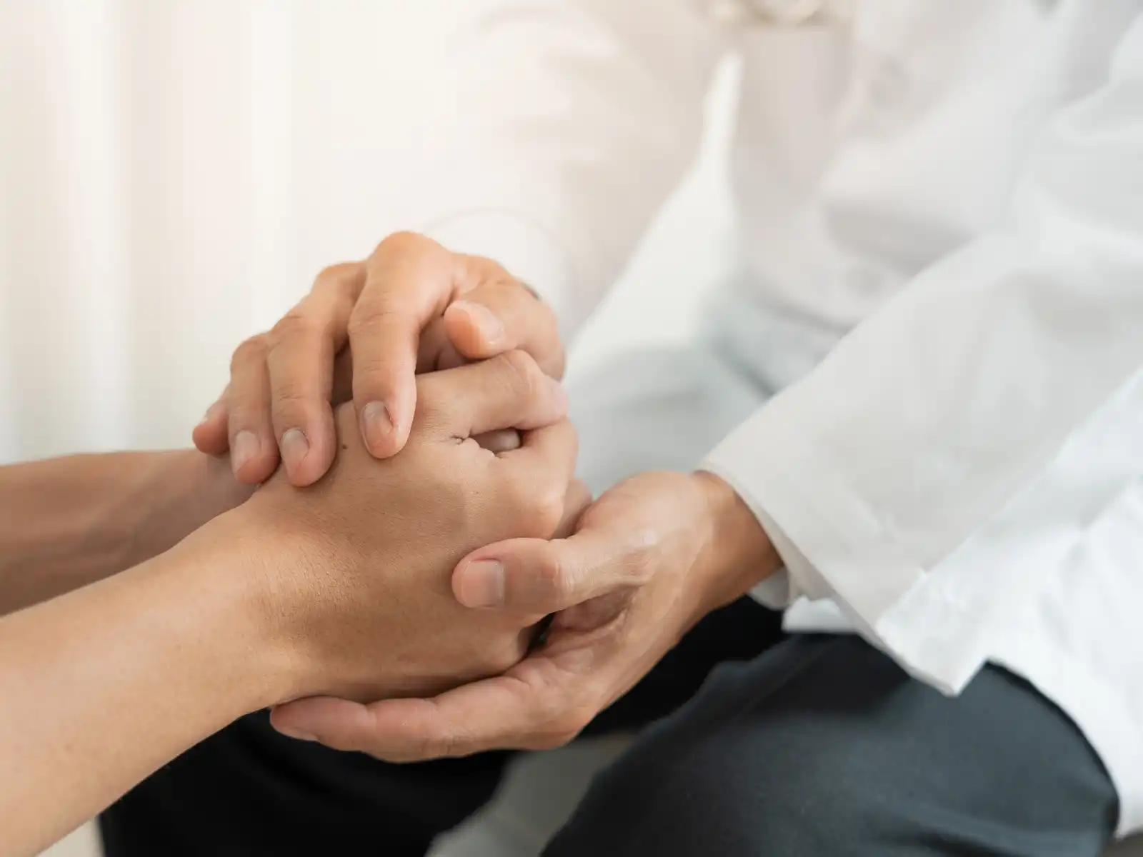 A close-up of two people holding hands in a supportive and comforting manner, symbolizing the emotional connection and trust fostered through Emotionally Focused Therapy (EFT) in Los Angeles.