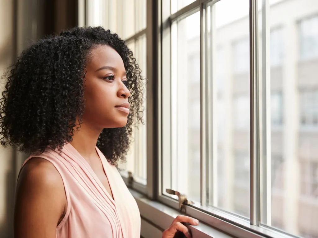 Thoughtful woman gazing out a window during a quiet moment, symbolising personal reflection and therapy in Los Angeles