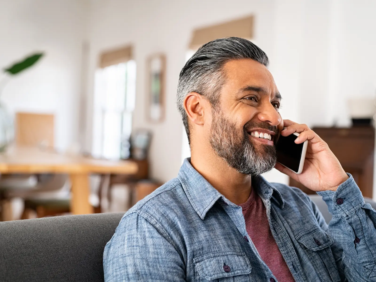 Smiling man on a phone call at home, representing a therapy consultation in Los Angeles